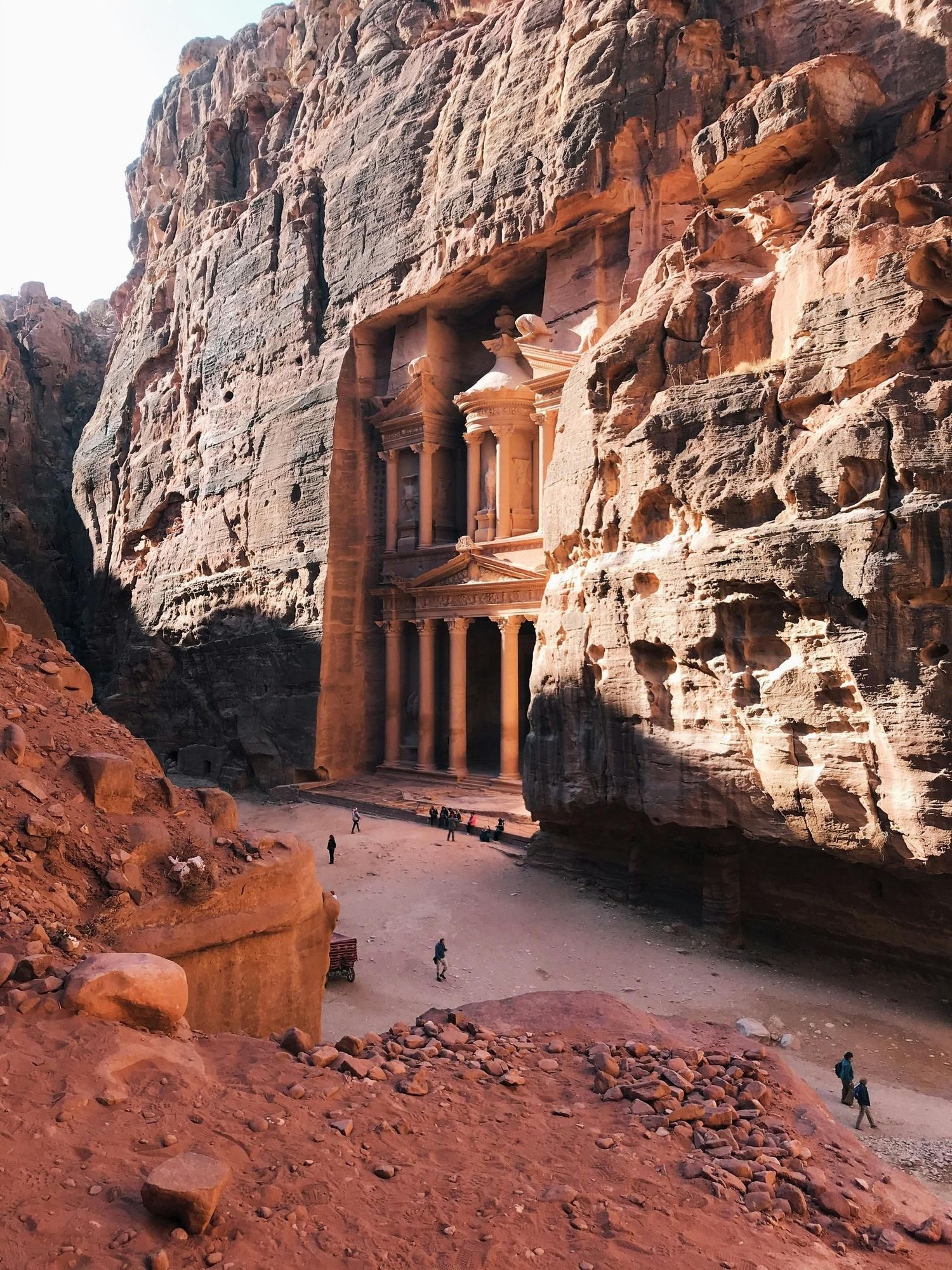 Ancient rock-cut temple facade carved into red sandstone canyon walls