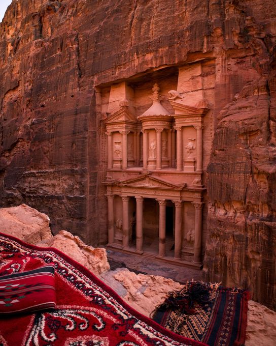 Ancient rock-cut temple facade carved into red sandstone canyon walls