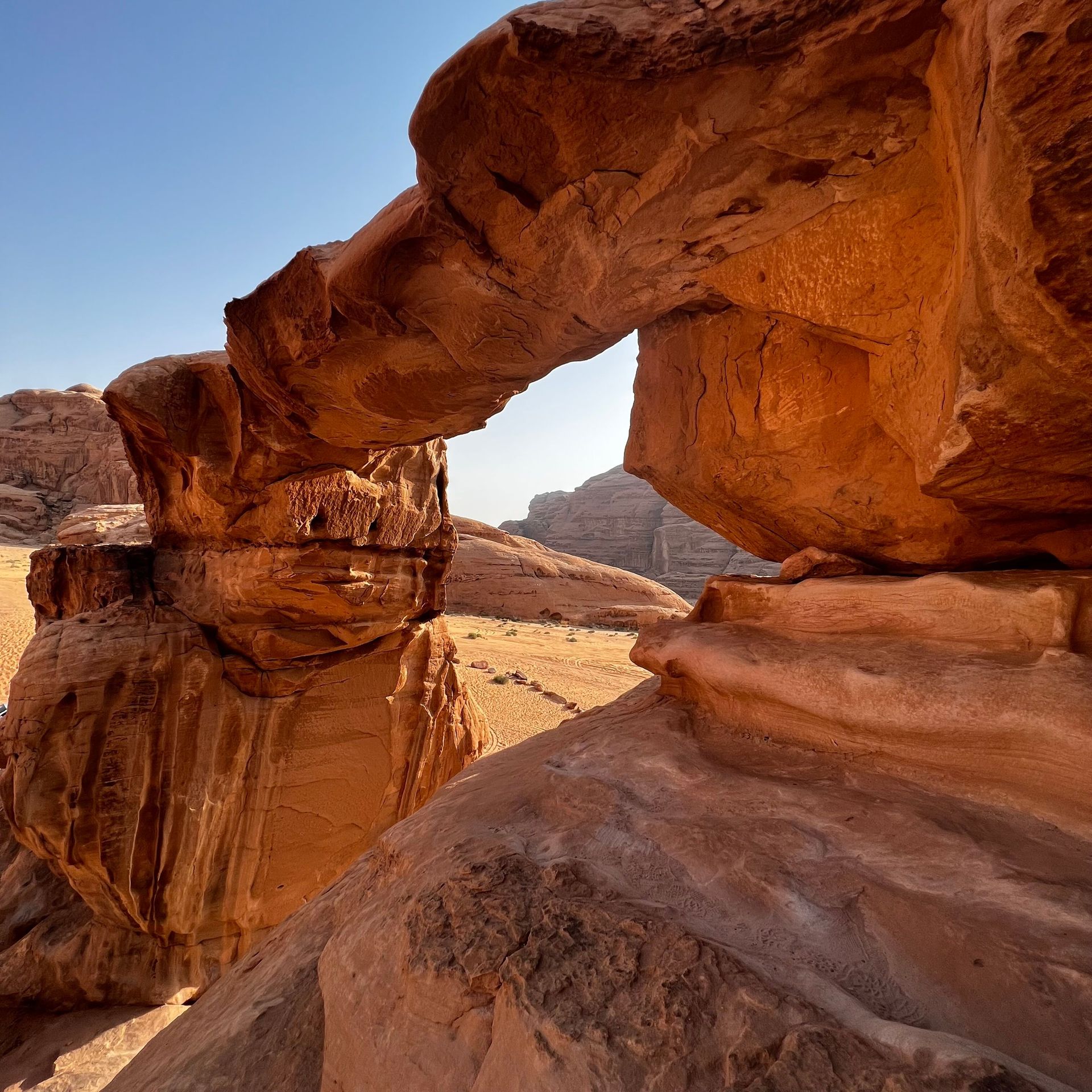 Red sandstone arch formation in a desert landscape under a clear blue sky