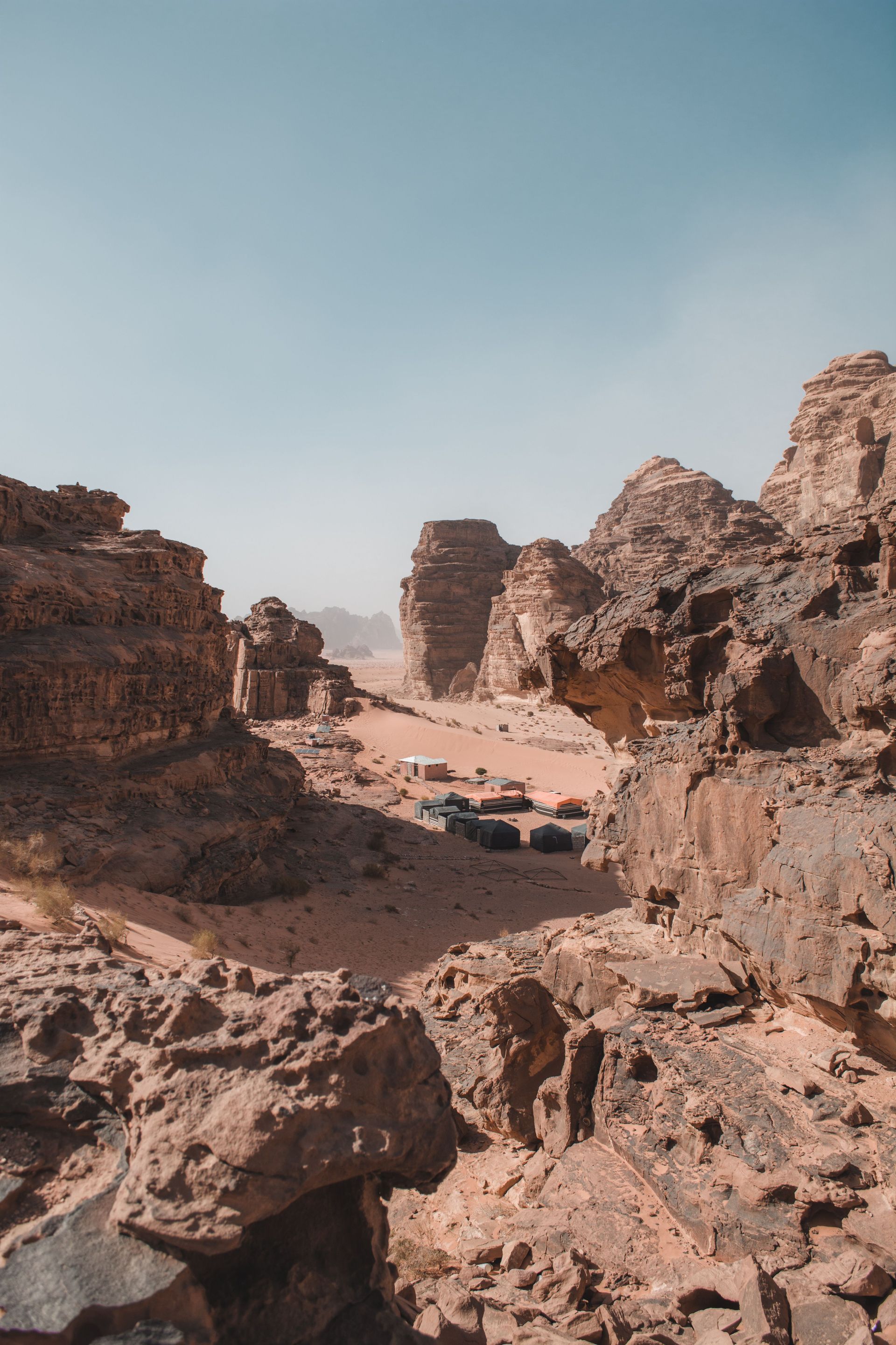 Rocky desert canyon with a sandy path under a clear blue sky