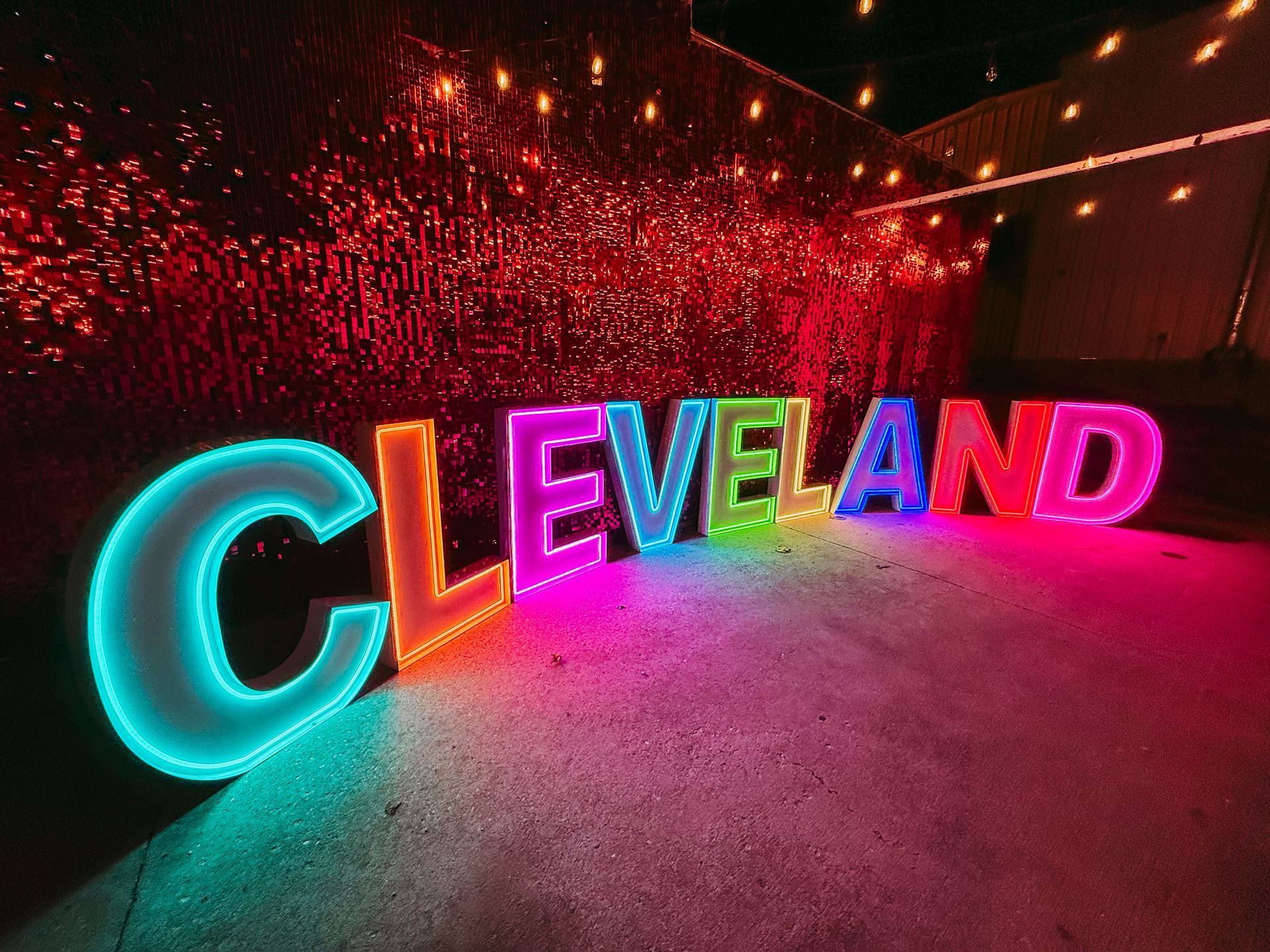 Color-changing LED marquee letters spelling “CLEVELAND” against a red sequin backdrop.
