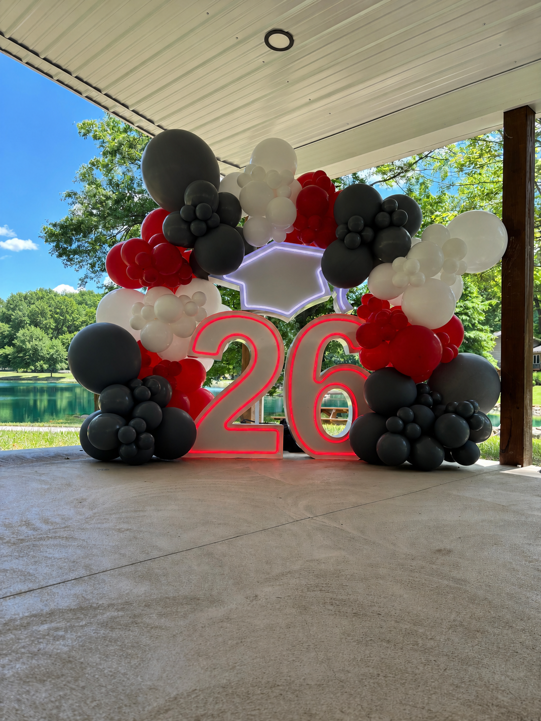 Illuminated “26” LED marquee numbers with a graduation cap and red, black, and white organic balloon garland.
