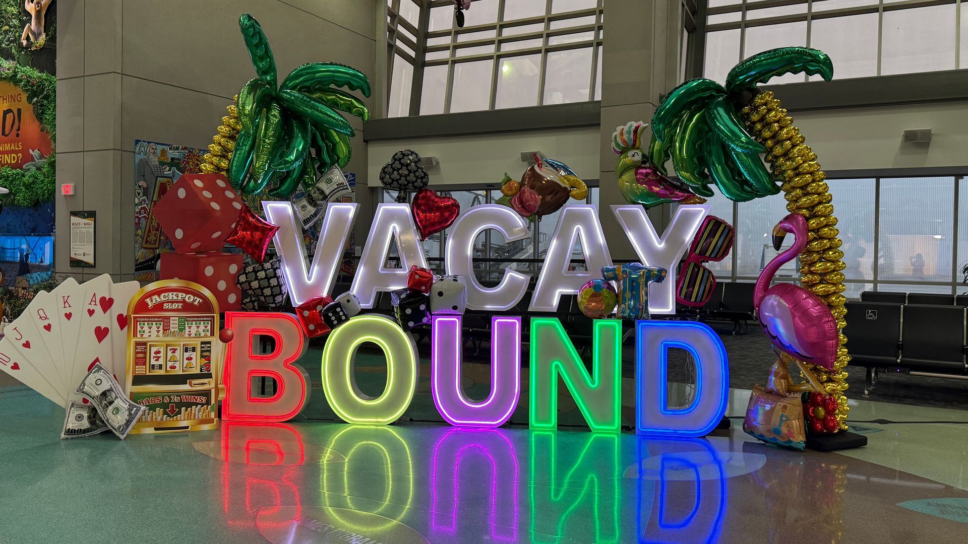 Colorful “VACAY VIBES” LED marquee letters surrounded by balloon palm trees, flamingos, flip-flops, and tropical decorations.
