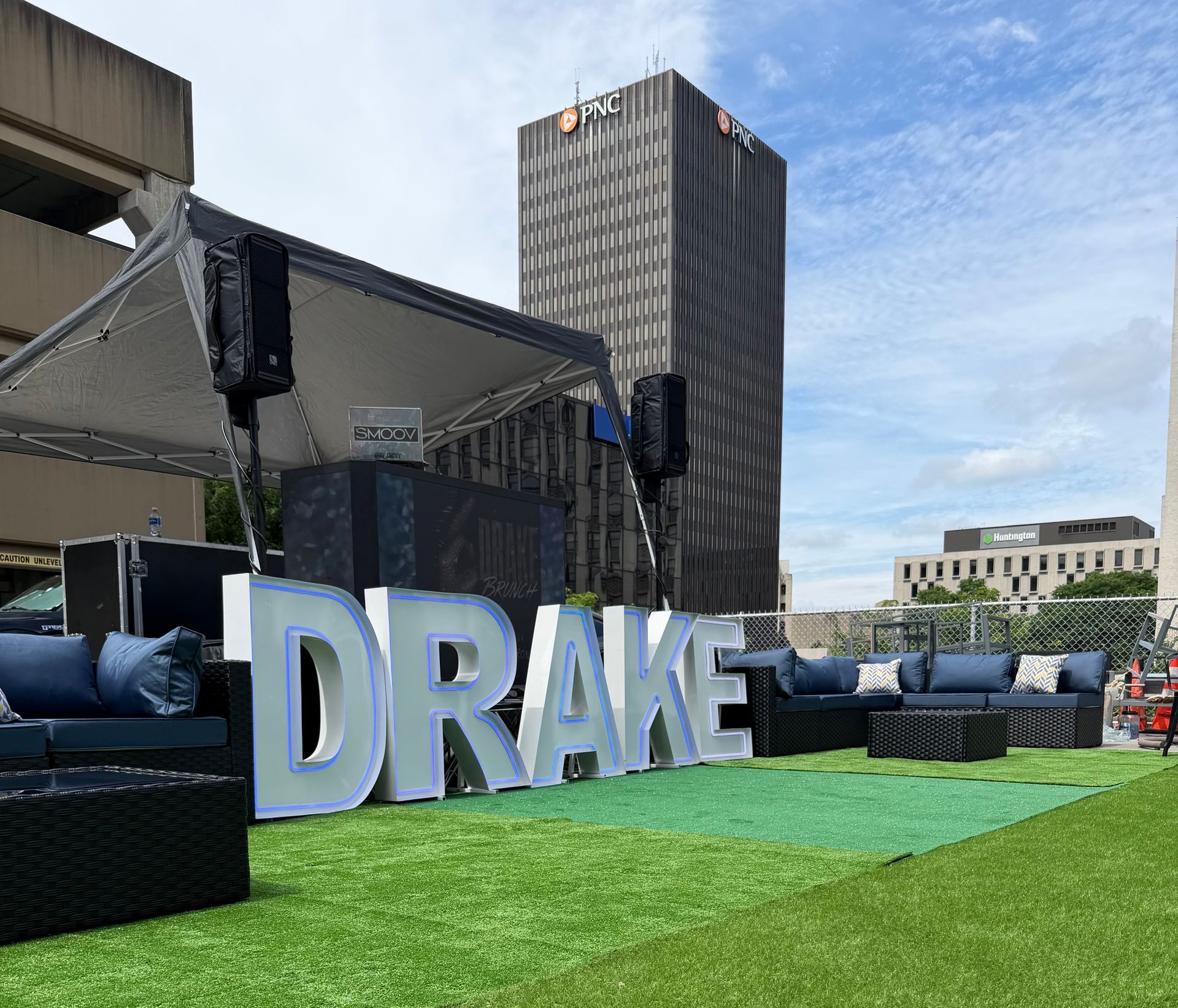 Oversized illuminated “DRAKE” marquee letters displayed at an outdoor rooftop corporate event.