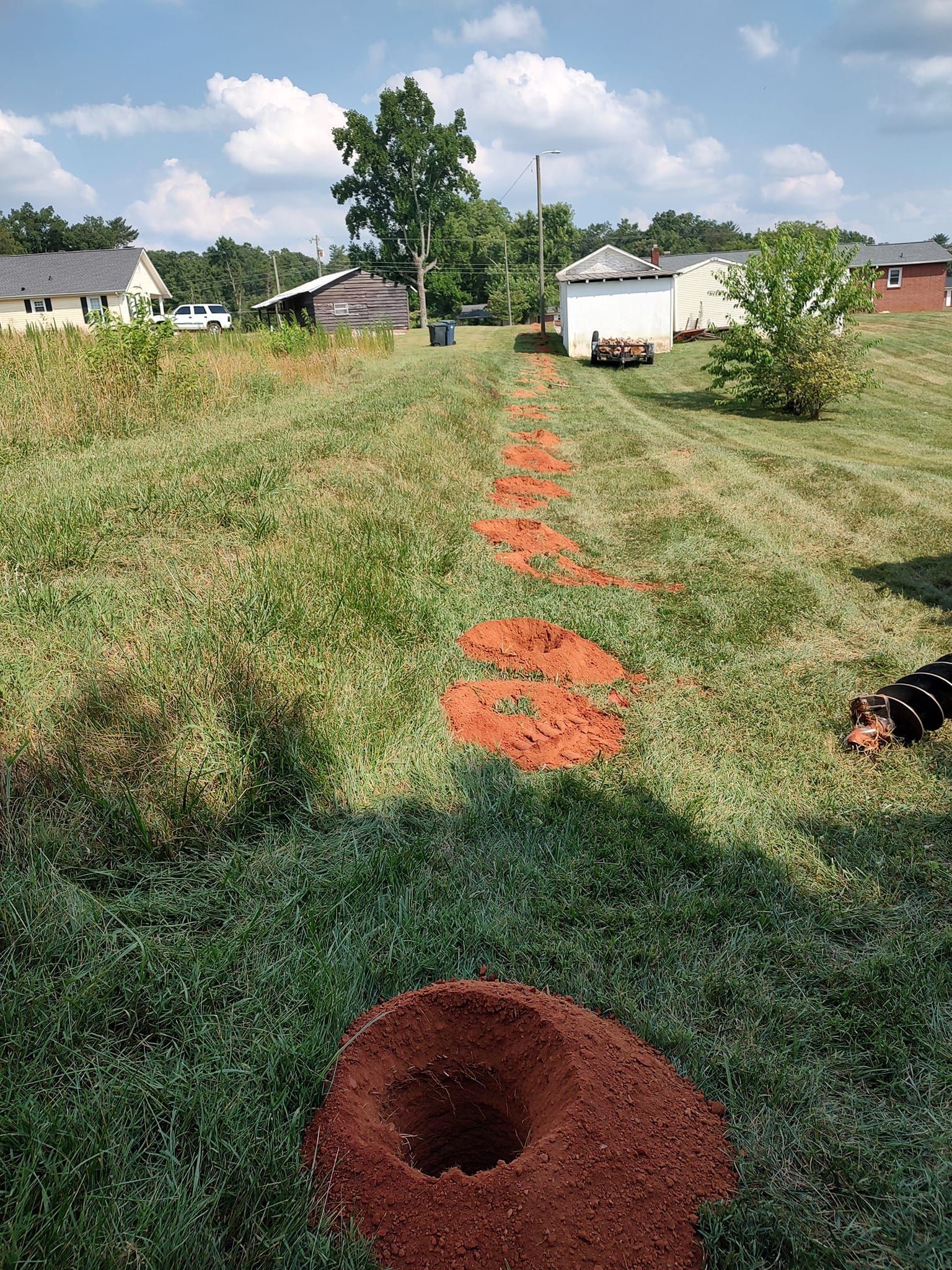 Orange stepping stones across a grassy yard toward a tree and houses in the distance