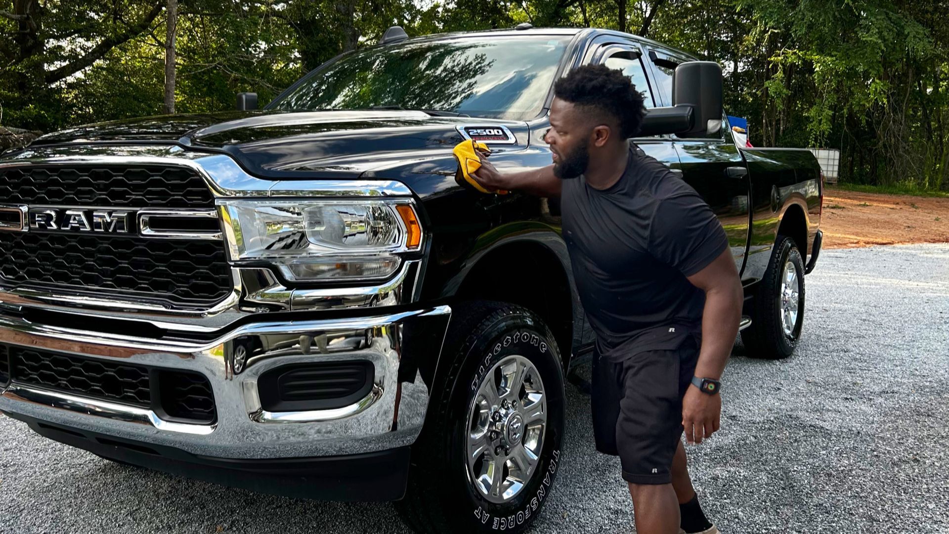 A man is cleaning the hood of a truck with a sponge.