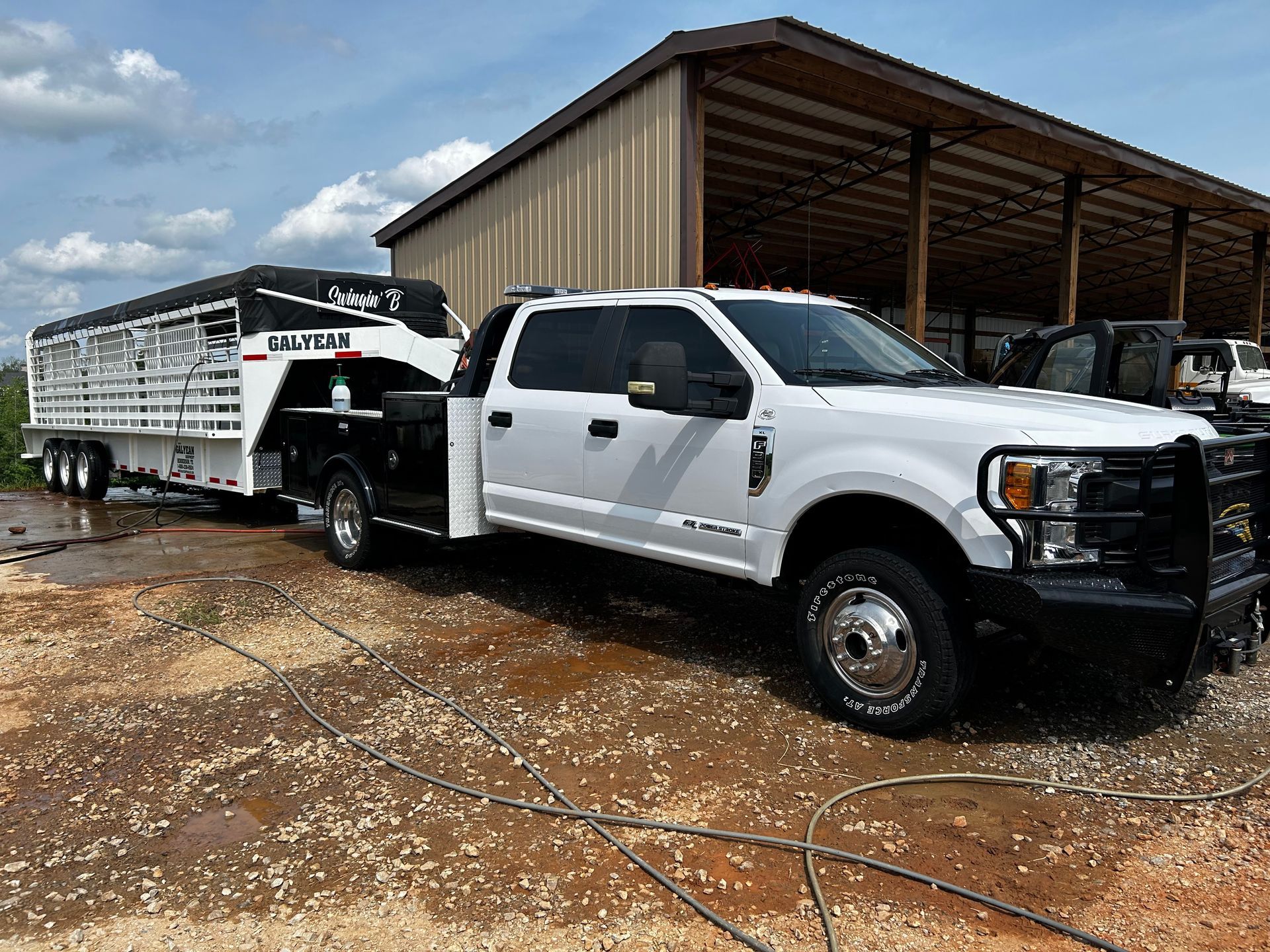 A white truck with a trailer attached to it is parked in front of a building.