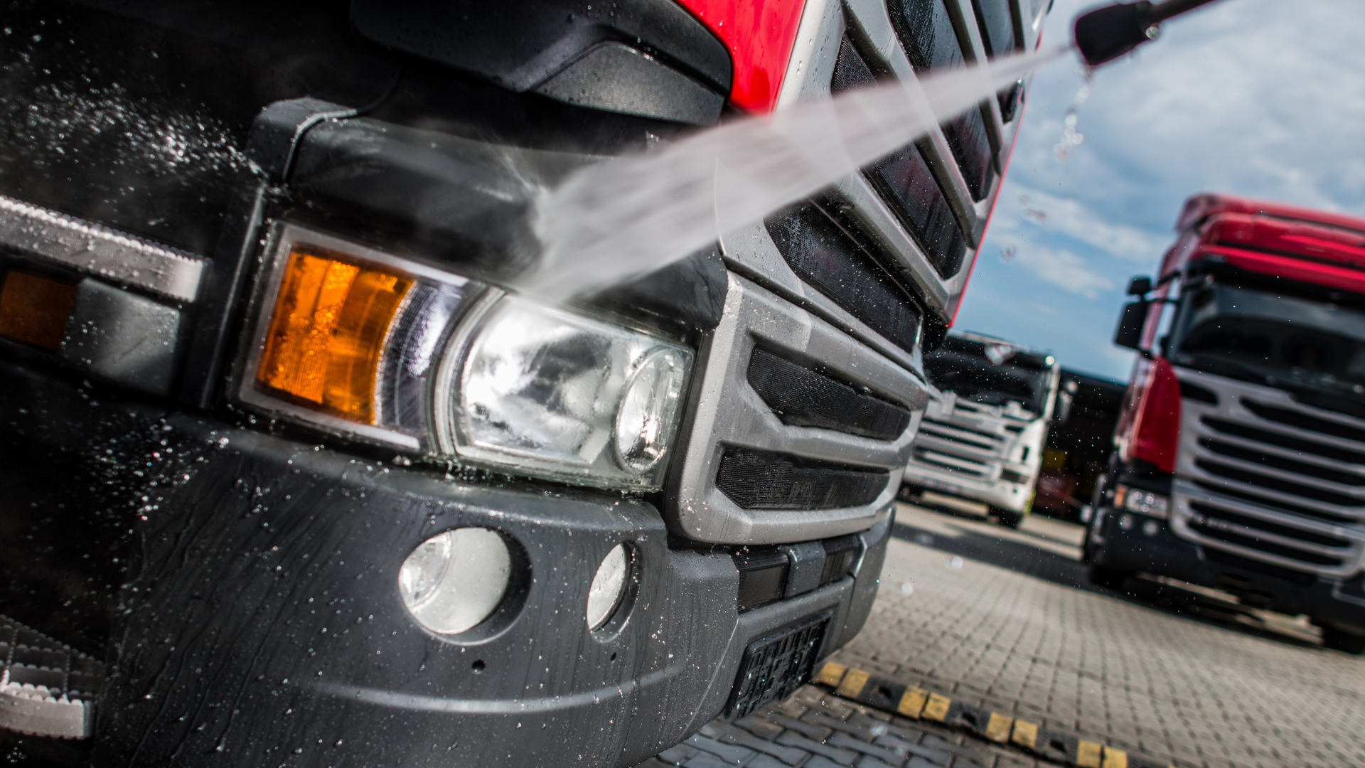 A truck is being cleaned with a high pressure washer.