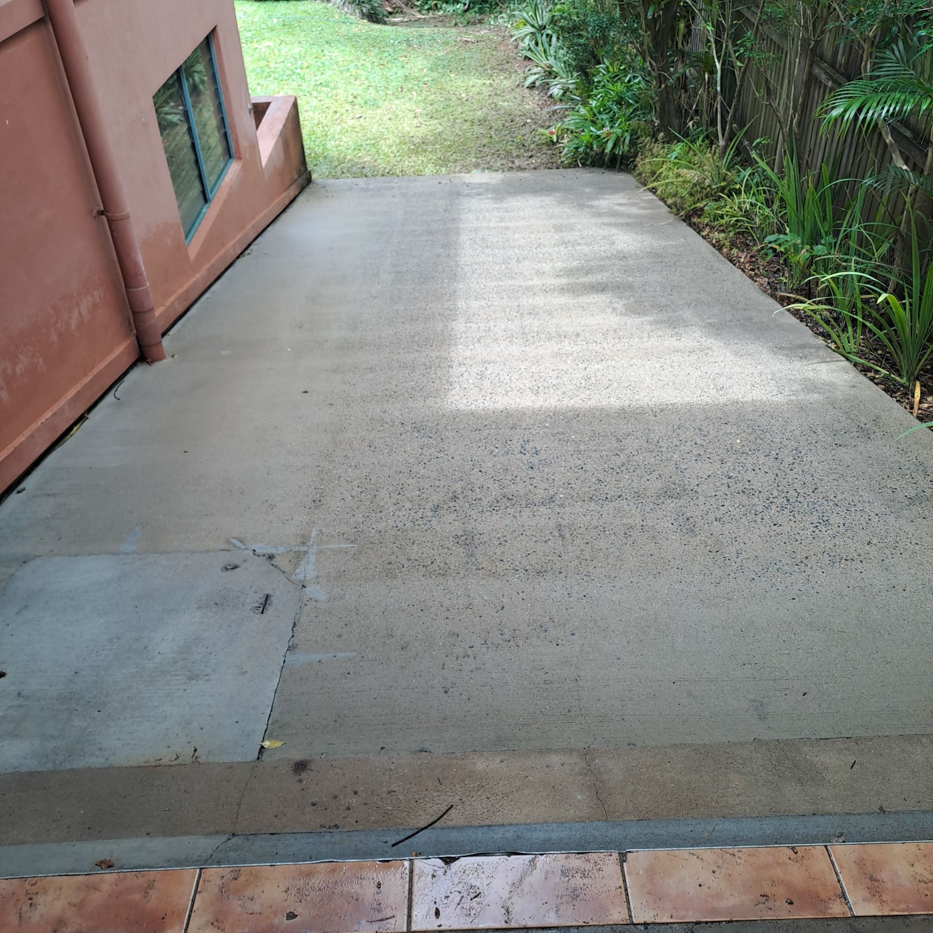 Concrete patio next to a red building with a small step and greenery in the background — Busy Bees Blasting in Trinity Beach, QLD