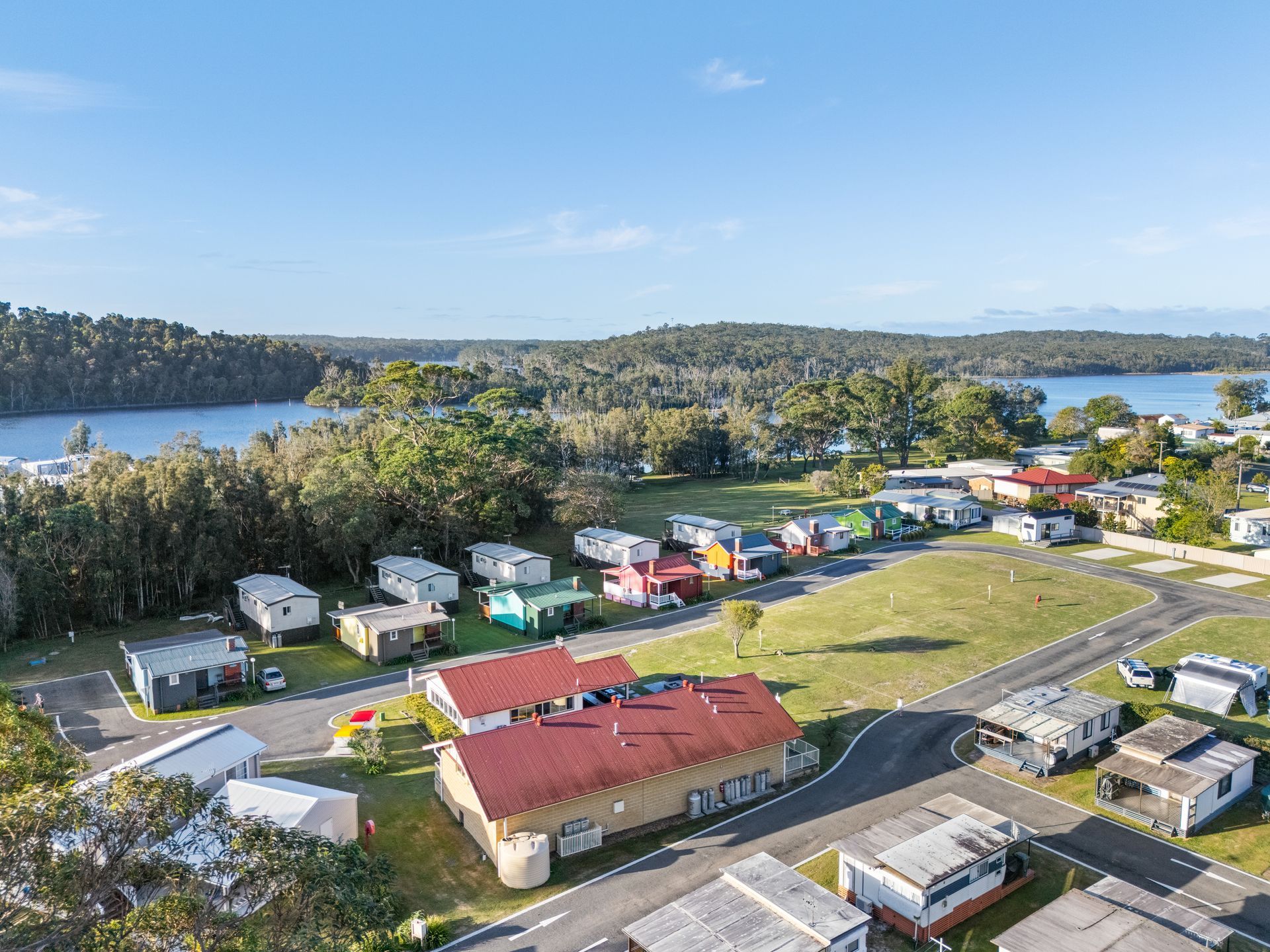 Aerial View of a Caravan Park With Colourful Caravans, a Building, Green Grass, Trees — SeaChange Parks Milton in Milton, NSW