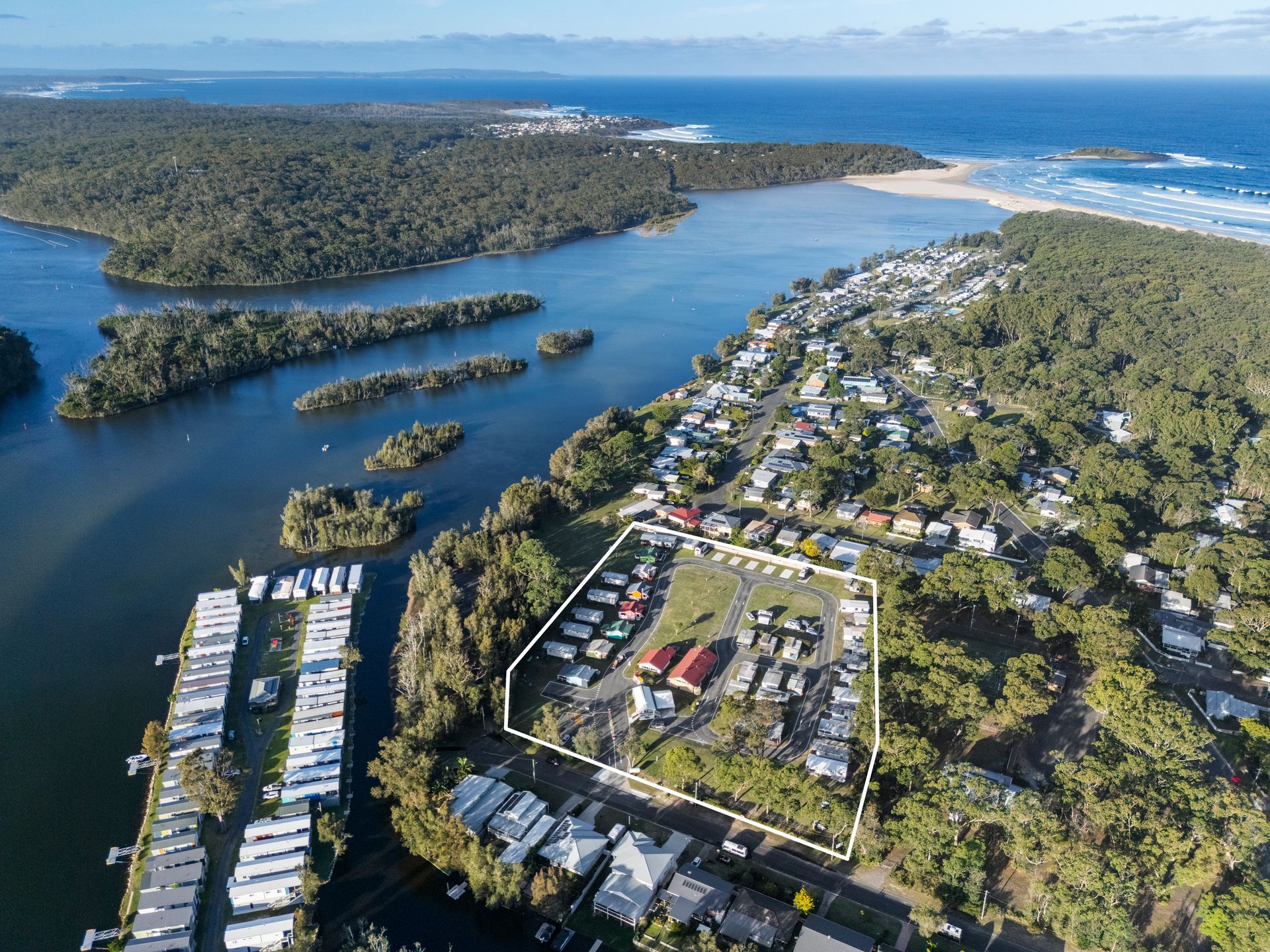 Aerial view of a coastal campground, bordered by water and forest — SeaChange Parks Milton in Lake Conjola, NSW