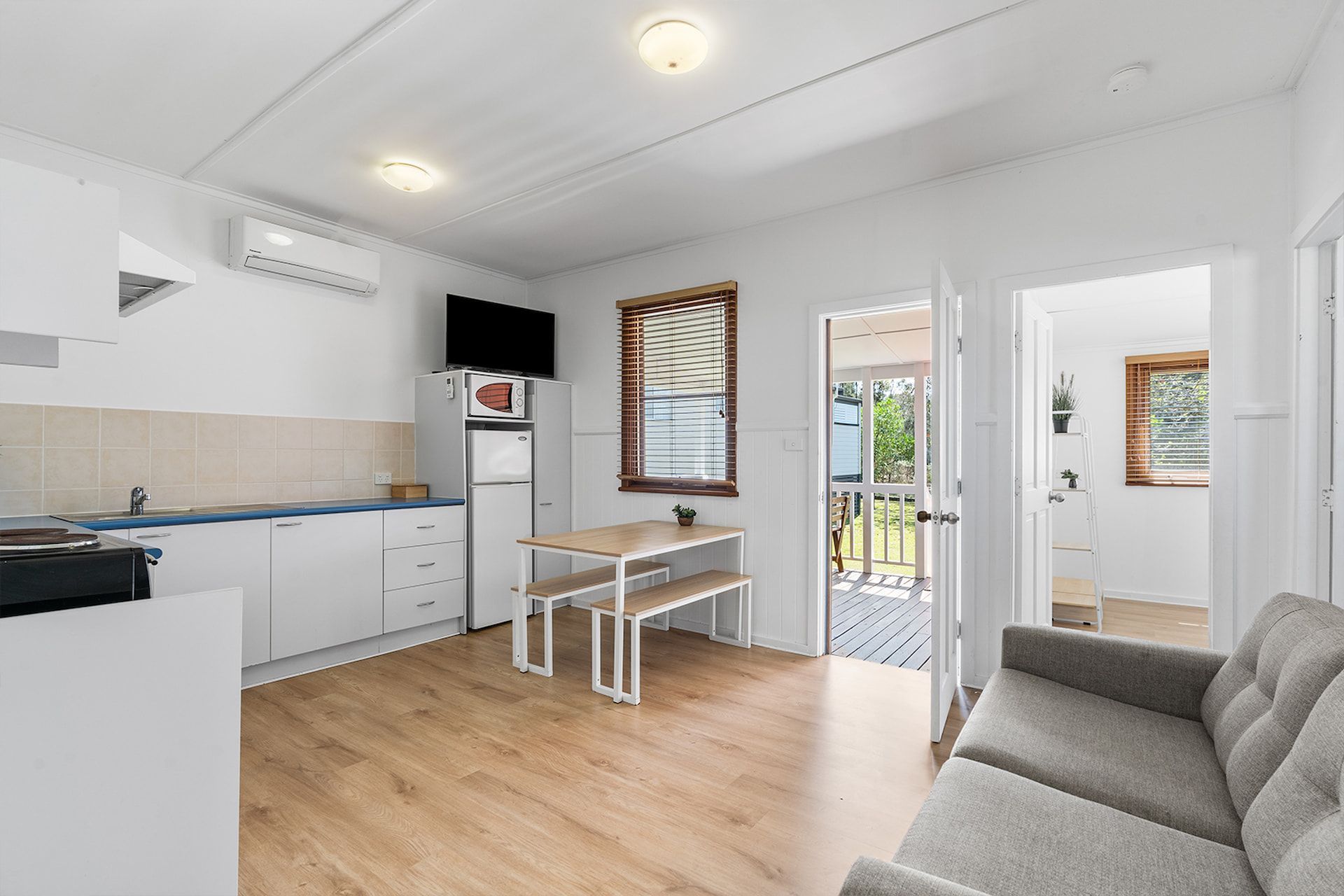 Small, Bright Apartment Interior with Kitchen, Dining Area, and Open Doorway — SeaChange Parks Milton in Lake Conjola, NSW