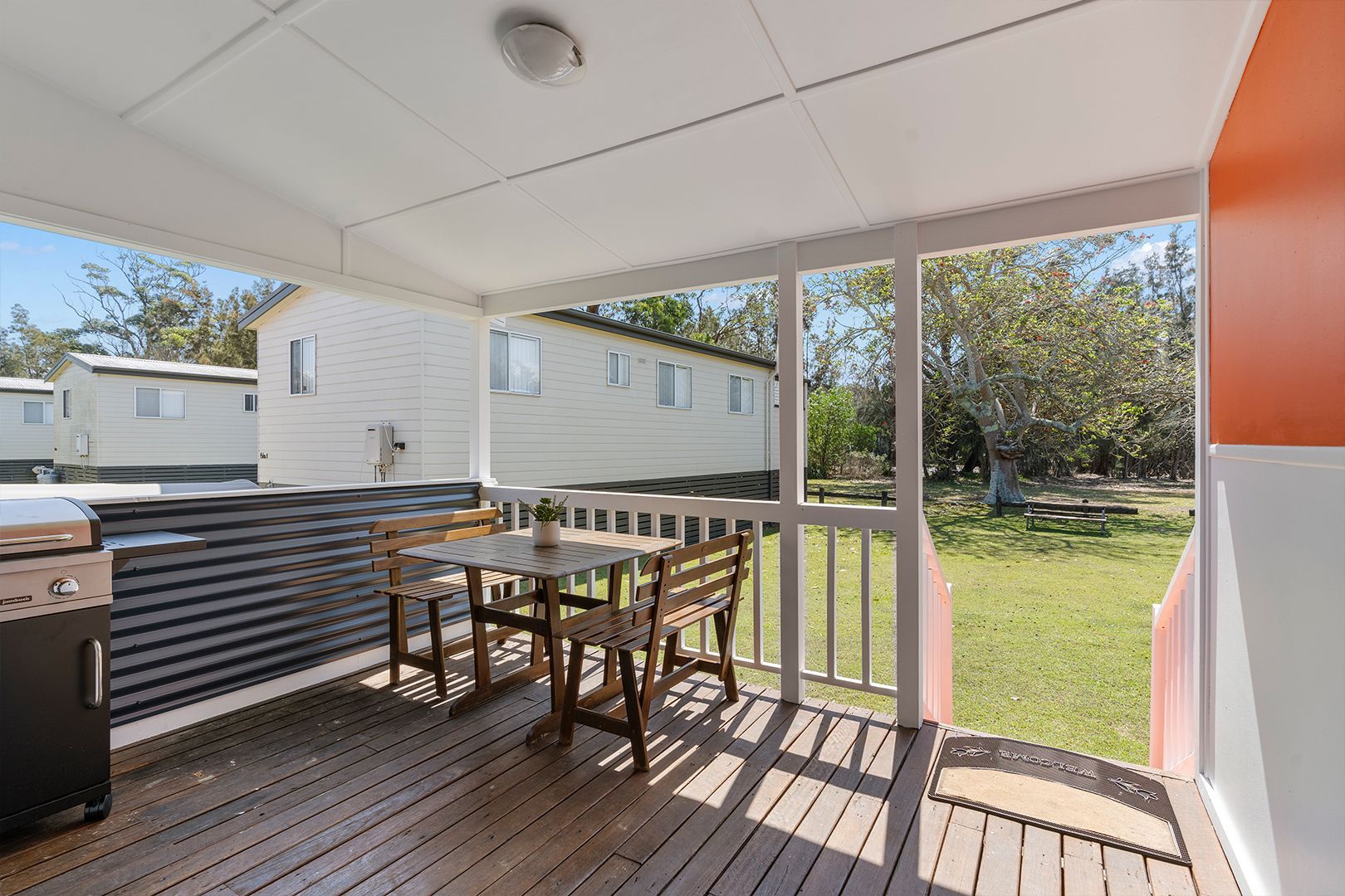 Covered Porch with Table and Chairs, Adjacent to A Grassy Yard and Mobile Homes — SeaChange Parks Milton in Lake Conjola, NSW