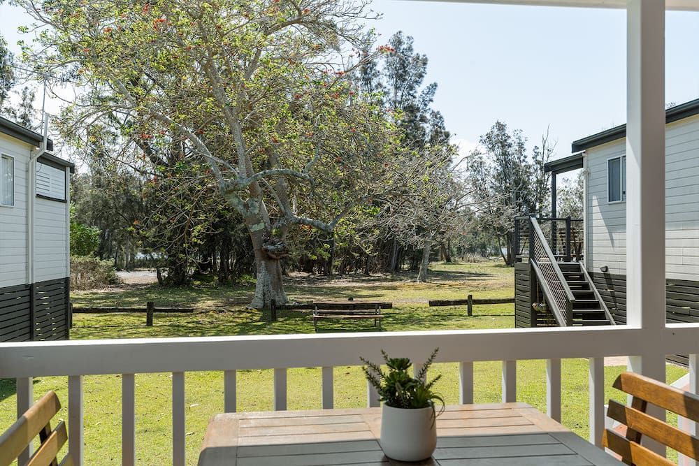 View from A Porch with A Table and Plant, Overlooking Cabins and Trees — SeaChange Parks Milton in Lake Conjola, NSW