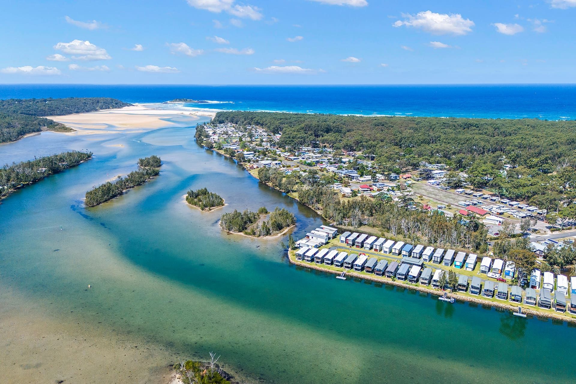 Aerial View: Coastal Town Bordering a River that Flows Into the Ocean — SeaChange Parks Milton in Lake Conjola, NSW