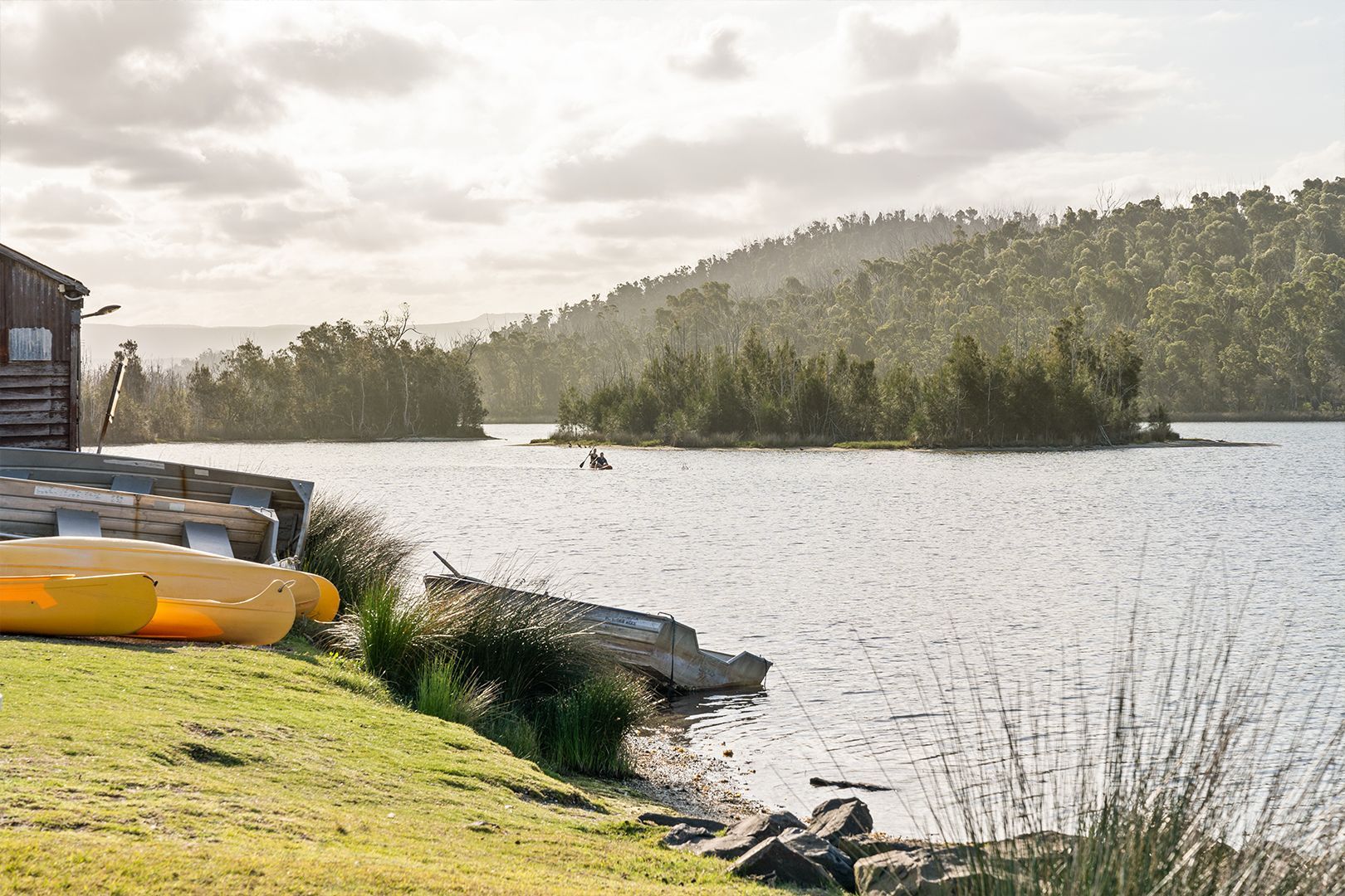 Lakeside Scene with Yellow Kayaks, Grassy Bank, and Forested Hills — SeaChange Parks Milton in Lake Conjola, NSW