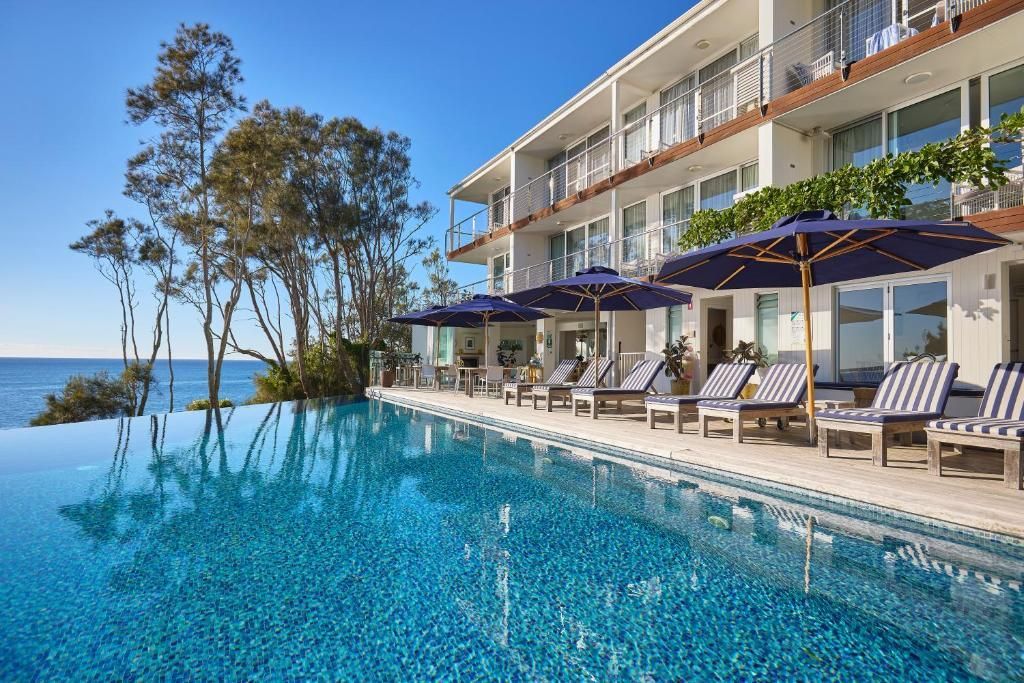 An Infinity Pool Overlooking the Ocean, With Rows of Lounge Chairs — SeaChange Parks Milton in Milton, NSW