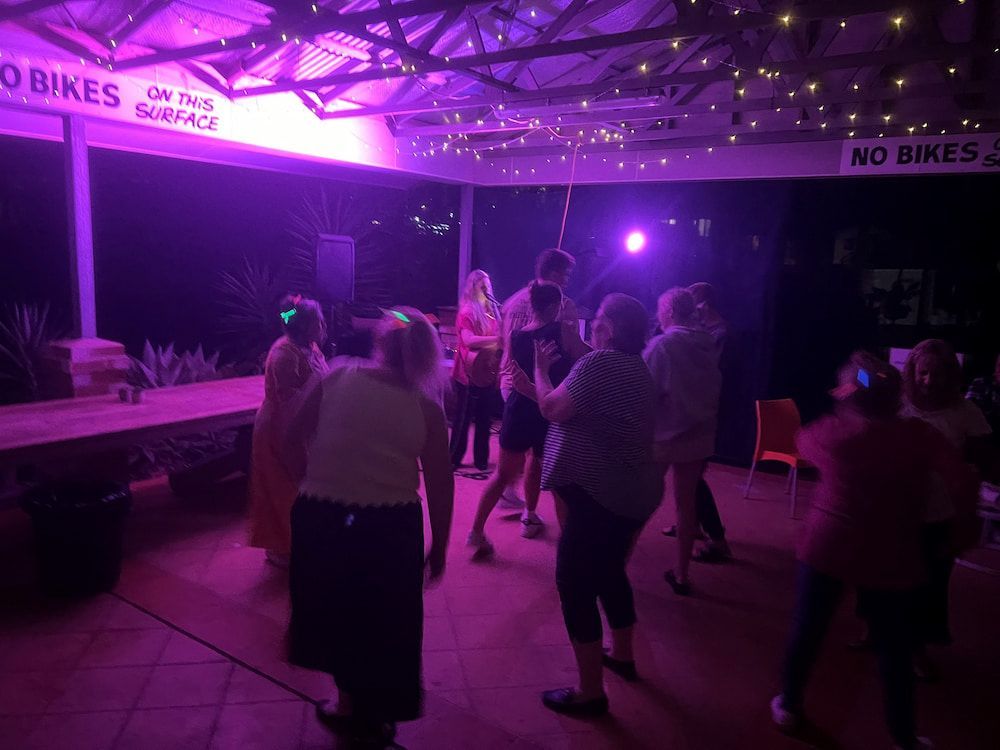 People Dancing Under Purple Stage Lights in an Outdoor Covered Area at Night — SeaChange Parks Milton in Milton, NSW