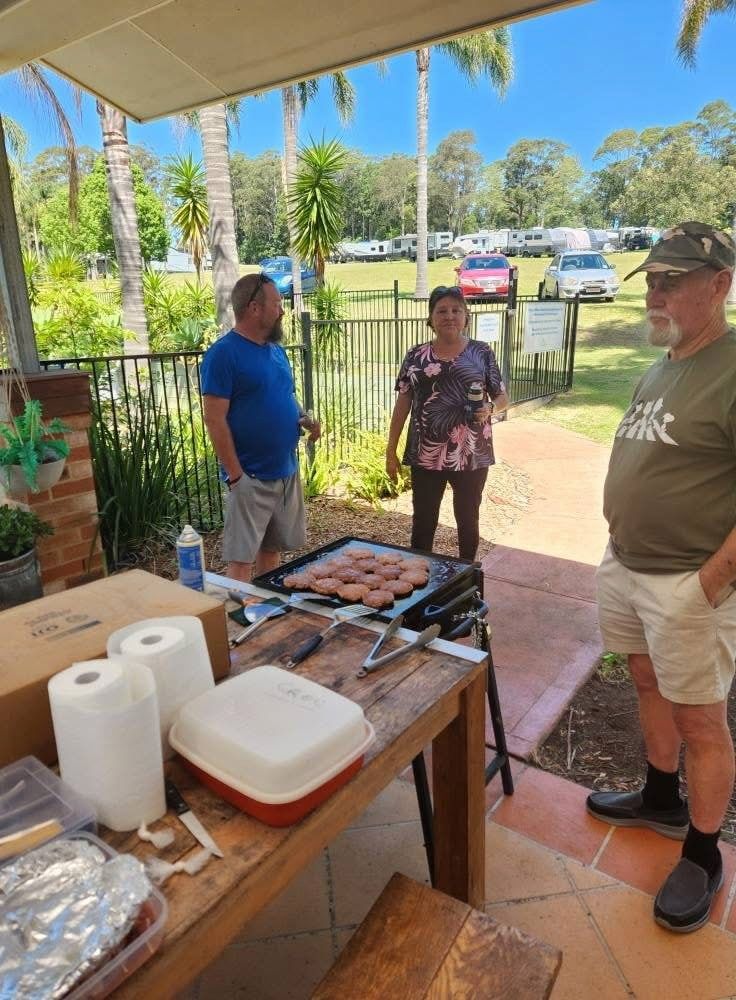 Three People Stand Near a Grill Cooking Food Outdoors — SeaChange Parks Milton in Milton, NSW