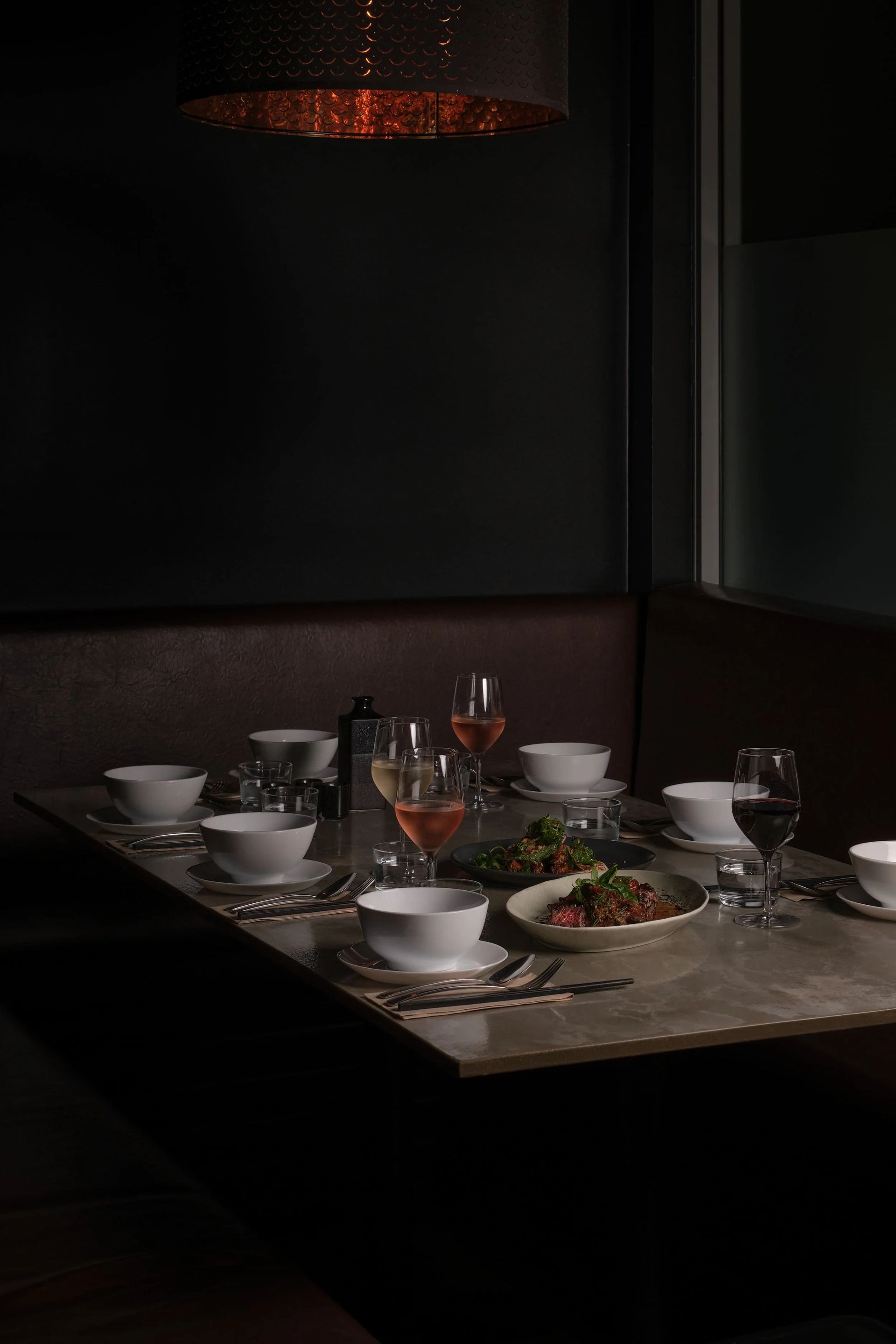 A Dimly Lit Table Set for a Meal in a Dark, Intimate Restaurant Booth — SeaChange Parks Milton in Milton, NSW