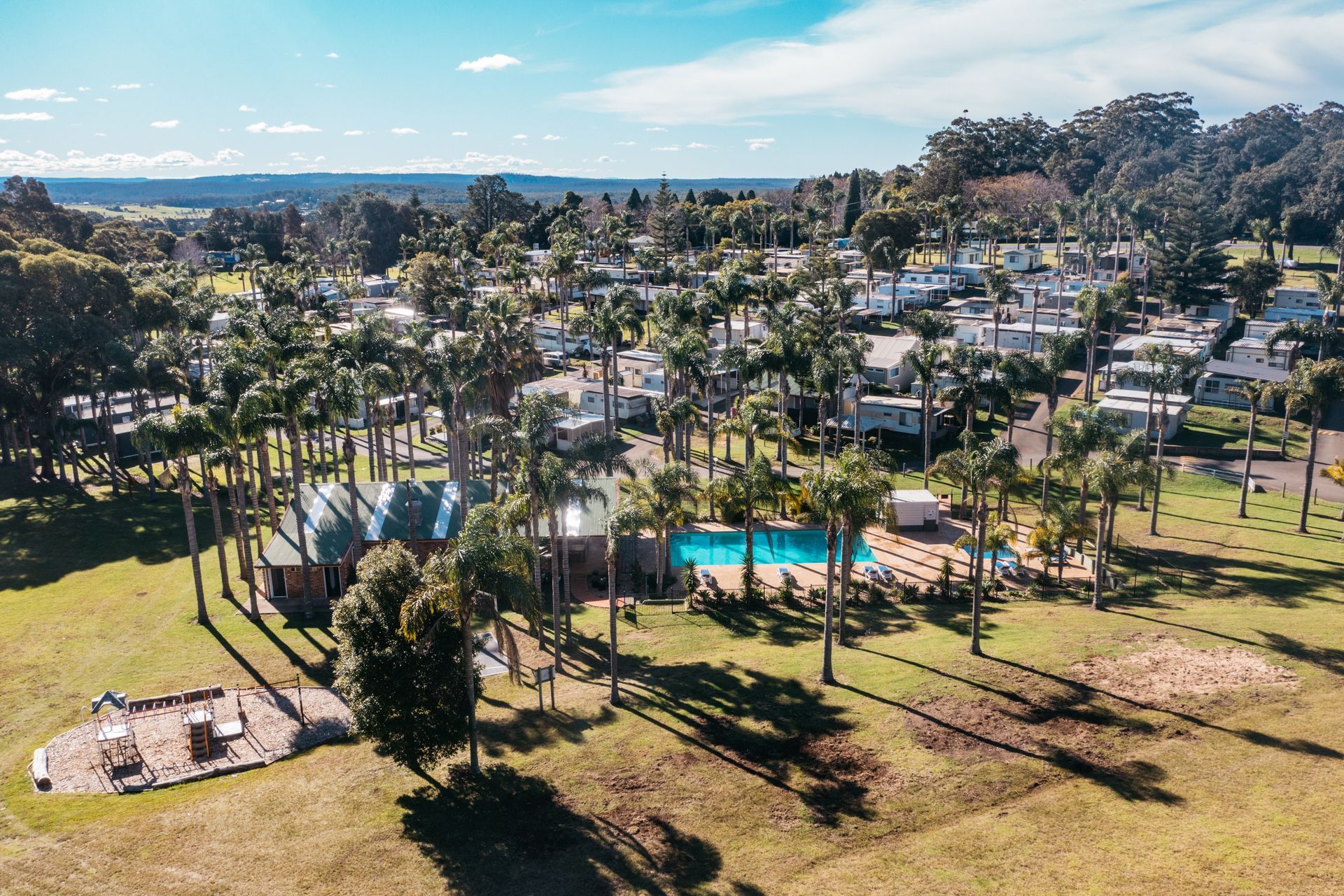 Aerial View of A Resort with A Pool, Cabins, and Tall Trees on A Grassy Field — SeaChange Parks Milton in Milton, NSW