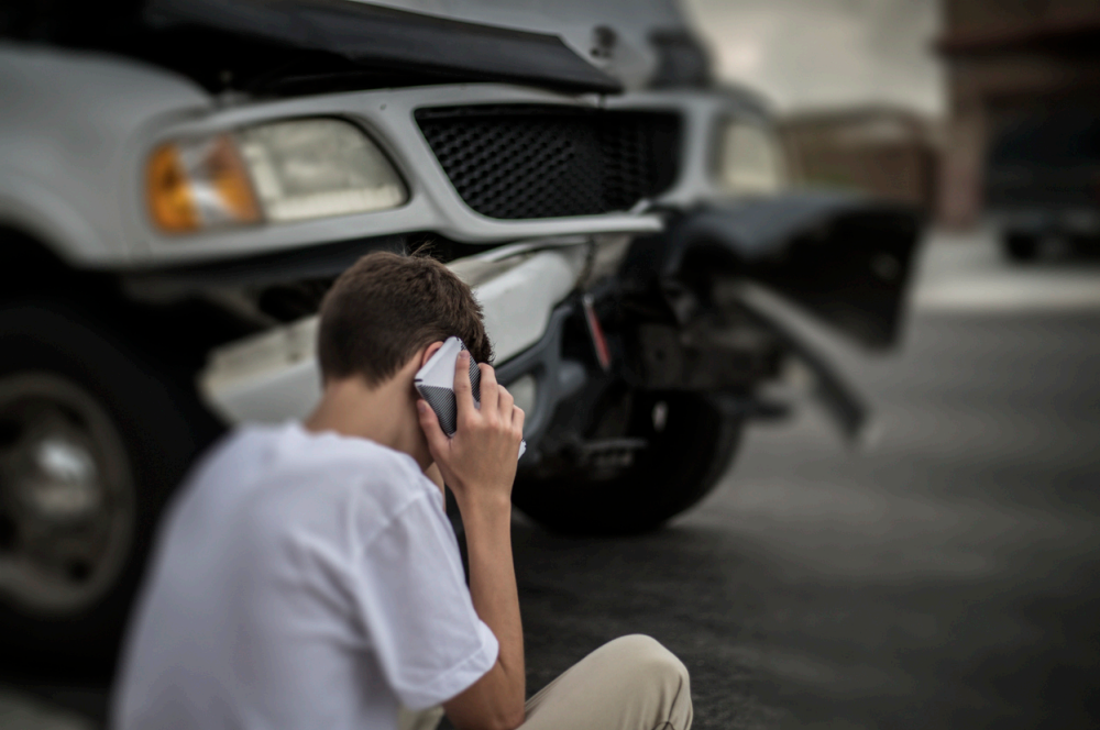 Man on phone beside a damaged pickup truck after a car accident.