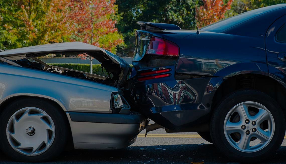 Two cars are involved in a car accident on the side of the road.
