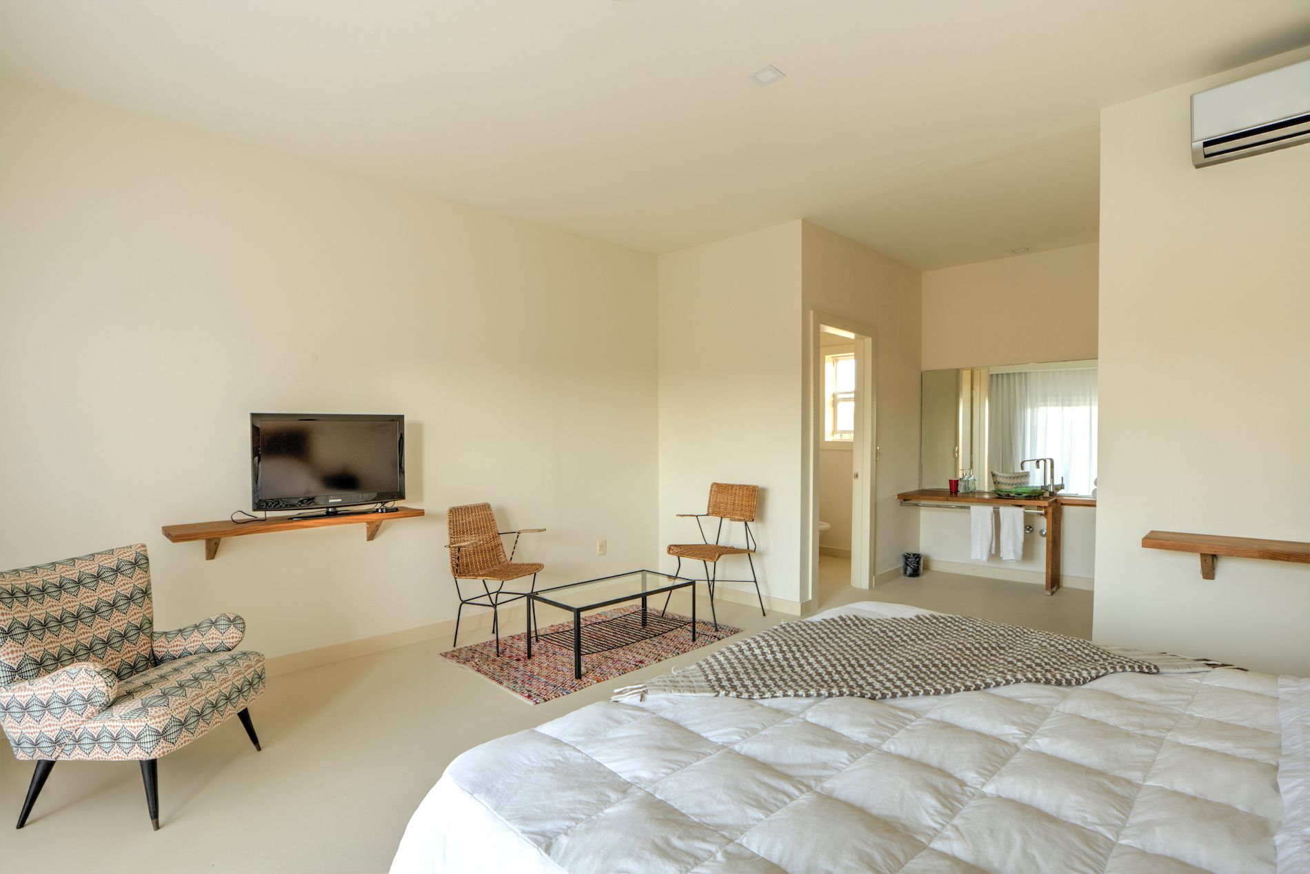 Un dormitorio con una cama, sillas, mesa y televisión.