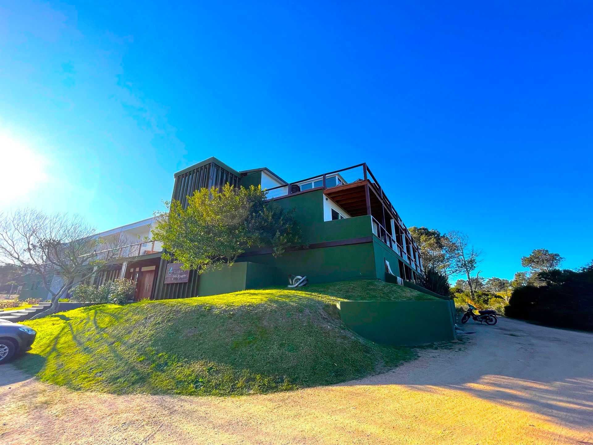 Una gran casa verde está situada en la cima de una colina cubierta de hierba.