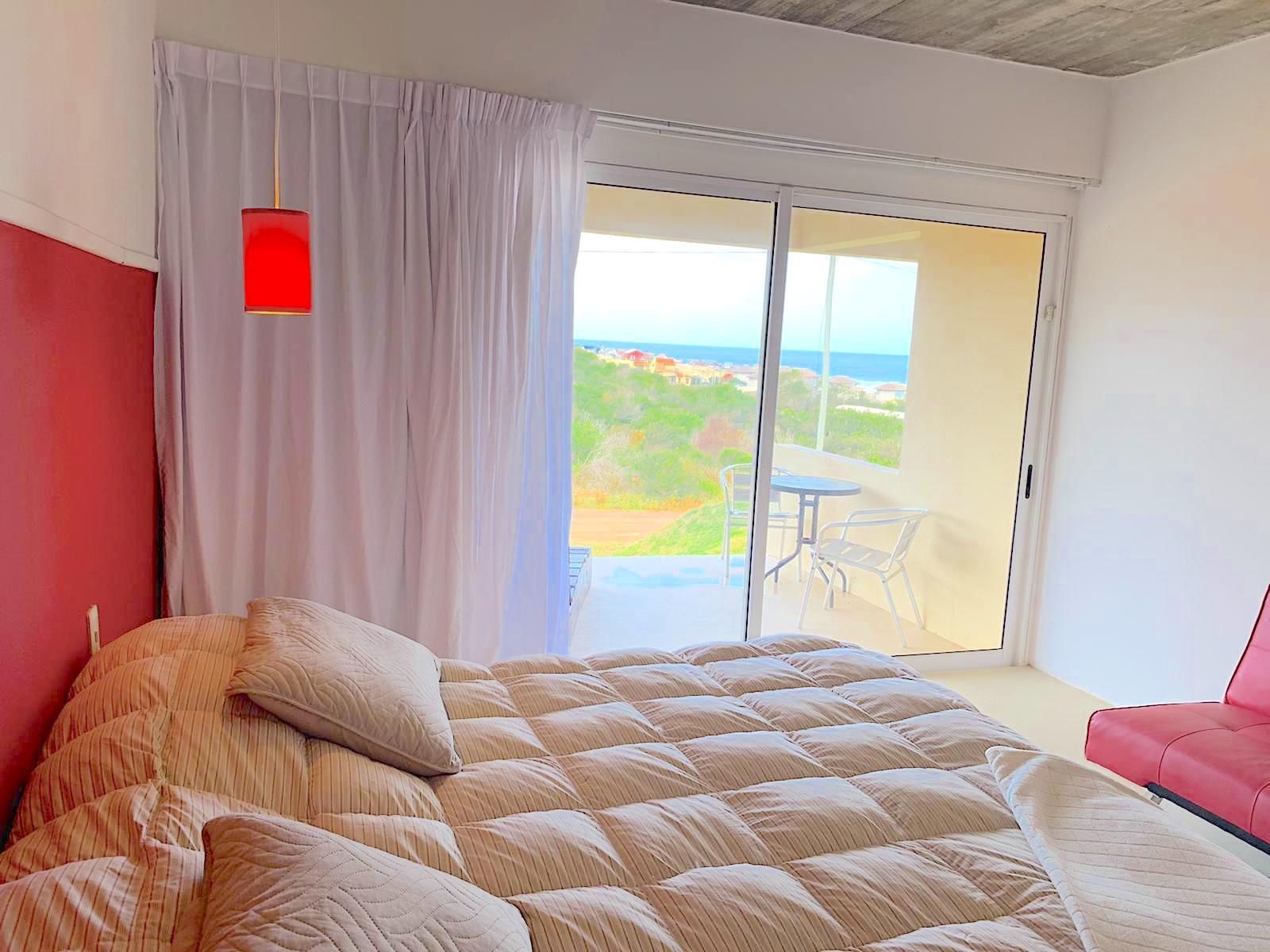 Un dormitorio con una cama grande y una puerta corrediza de vidrio que conduce a un balcón.