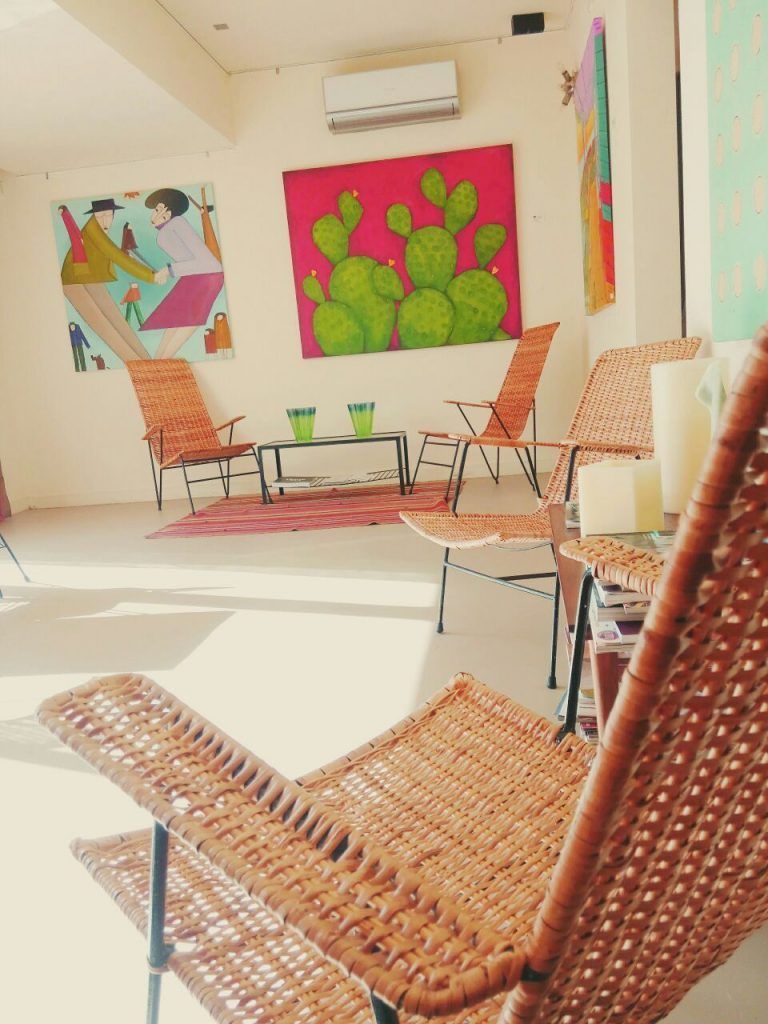 Una habitación con sillas de mimbre y un cuadro de cactus en la pared.