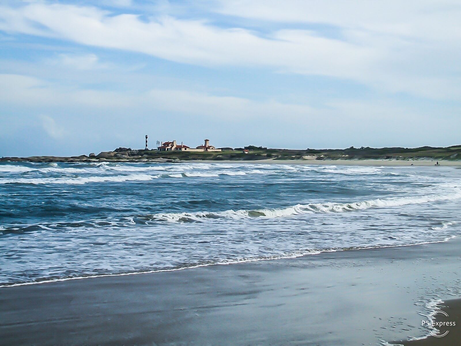 Una playa con un faro a lo lejos