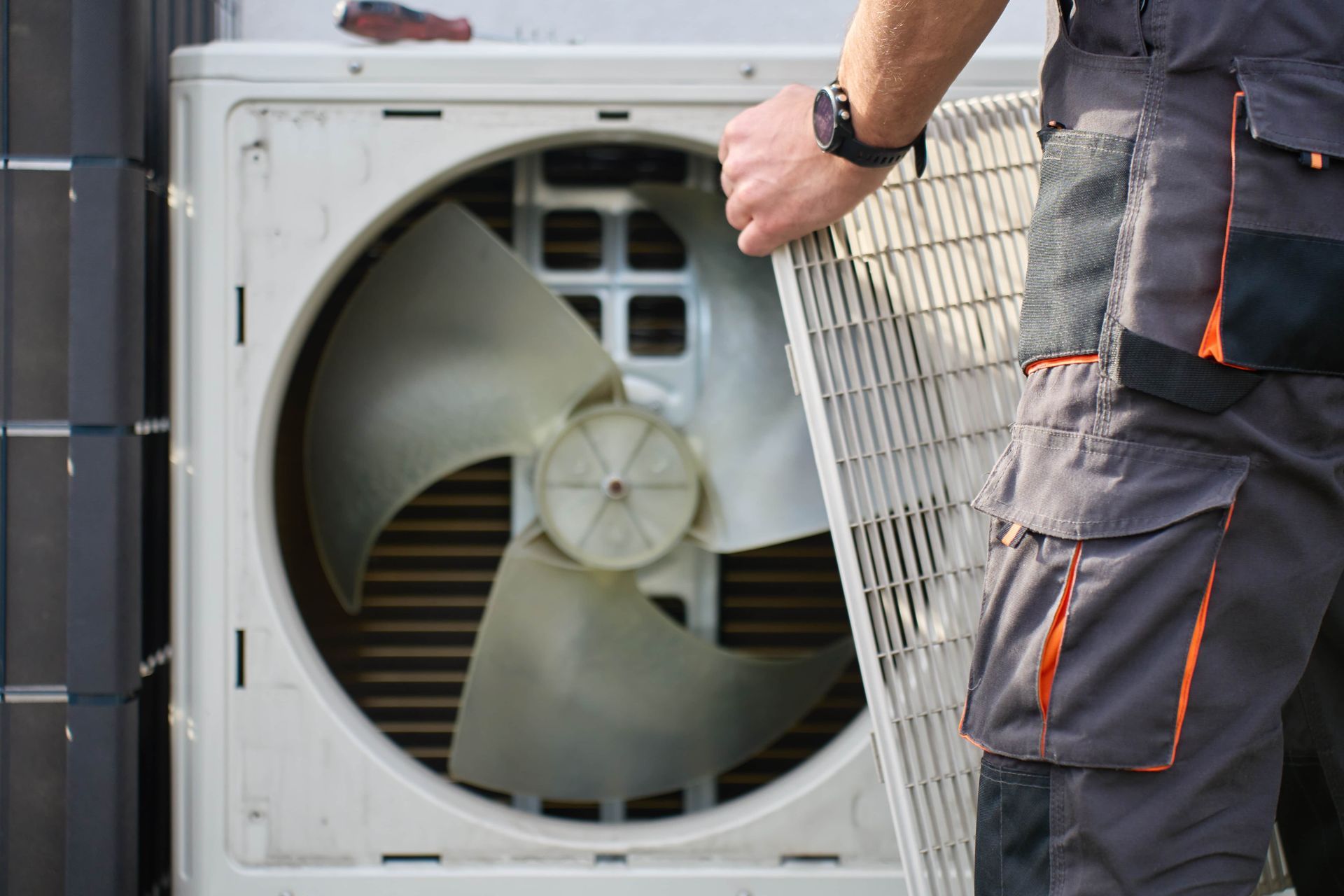 Technician inspecting a large industrial fan inside an HVAC unit outdoors