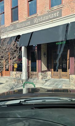 Restaurant storefront with black awning, brick facade, and sidewalk entrance seen from a car
