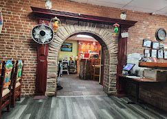 Rustic brick restaurant entrance with arched doorway, warm lights, and wood counters inside