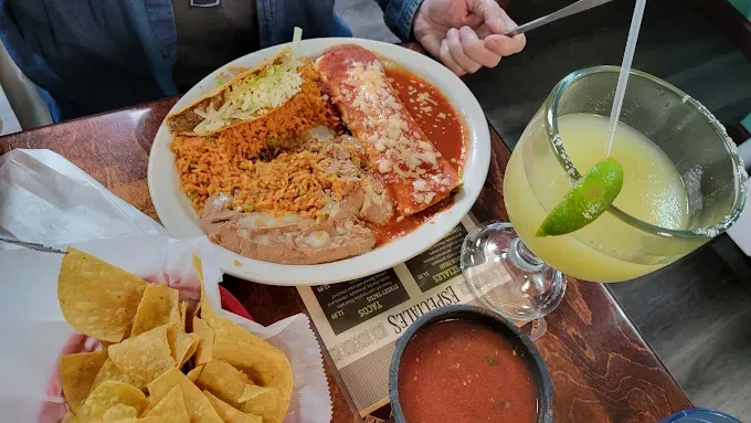 Mexican meal with enchiladas, chips, salsa, and a margarita on a restaurant table