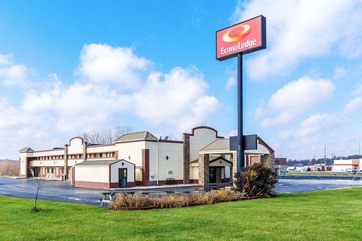 Red Roof Inn motel building with tall sign on a grassy roadside under a blue sky