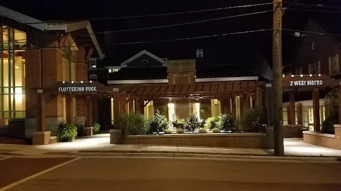 Night view of a brick hotel entrance with lit landscaping and signage across the street.