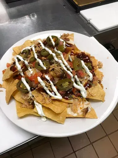 Plate of loaded nachos with salsa, beans, and white sauce on a countertop