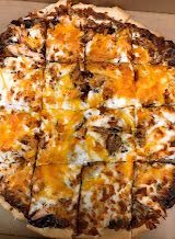 Close-up of a cheesy pizza with browned crust and sliced pieces