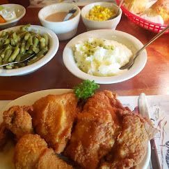 Plate of fried chicken with rice and side dishes on a restaurant table
