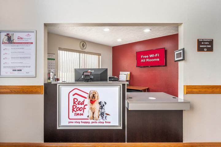 Reception desk in a clinic lobby with red accent wall, sign, computer, and brochure stand