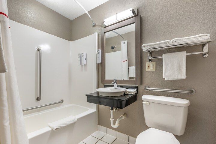 Accessible bathroom with shower, toilet, sink, grab bars, and towels