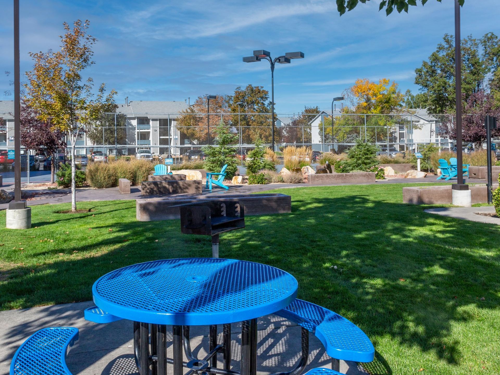 a blue picnic table with benches and a grill in a park .