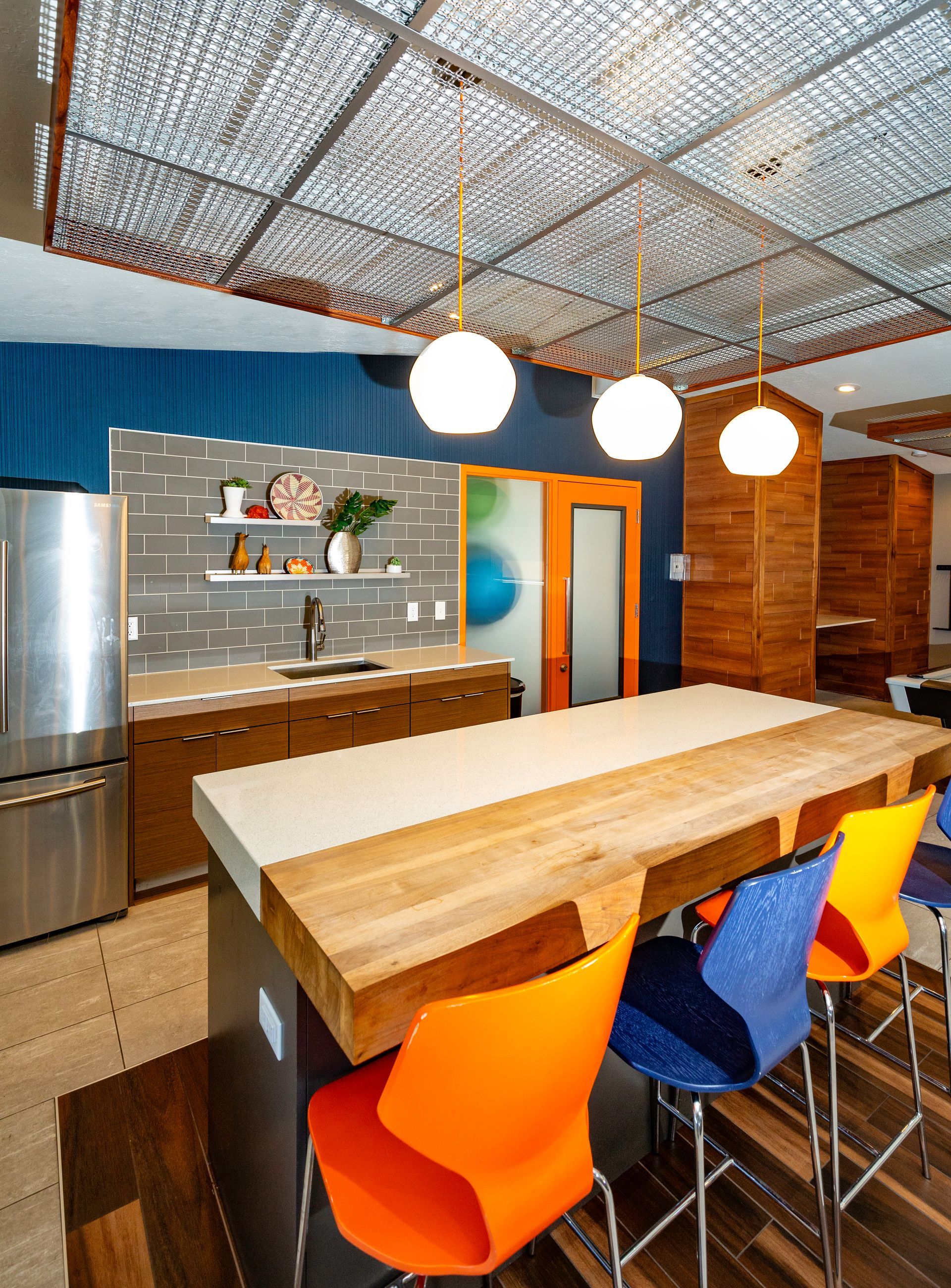 a kitchen with a long wooden table and colorful chairs