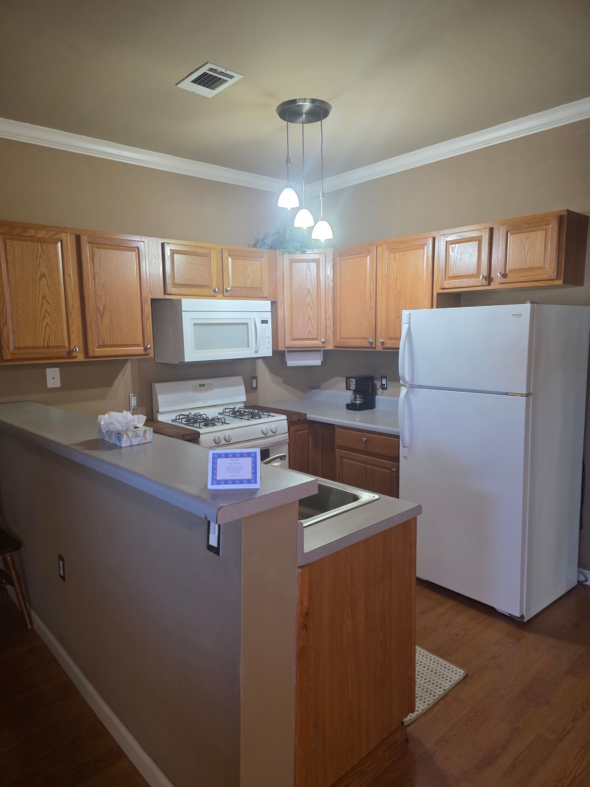 Kitchen with light-brown cabinets, white appliances, and a breakfast bar.