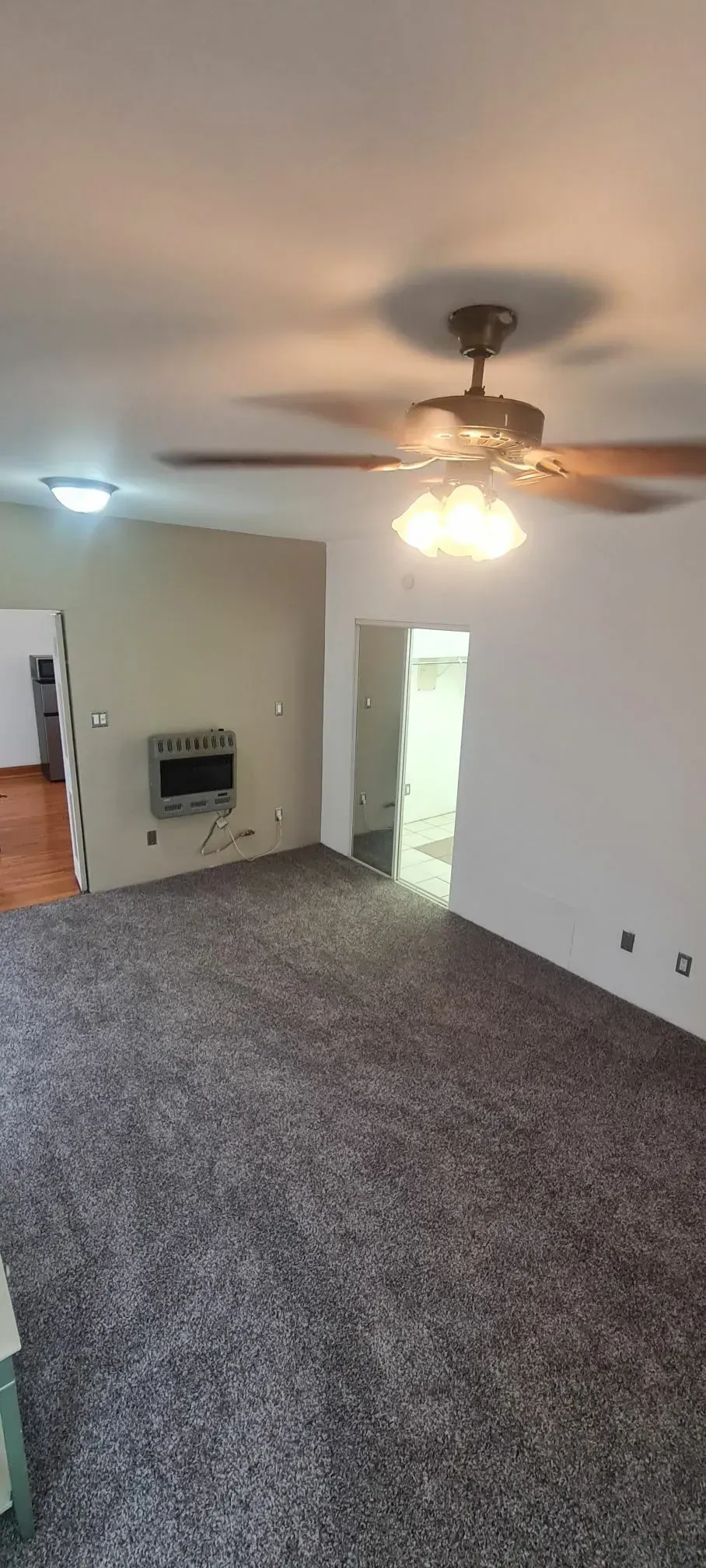 A living room with a ceiling fan and a flat screen tv.