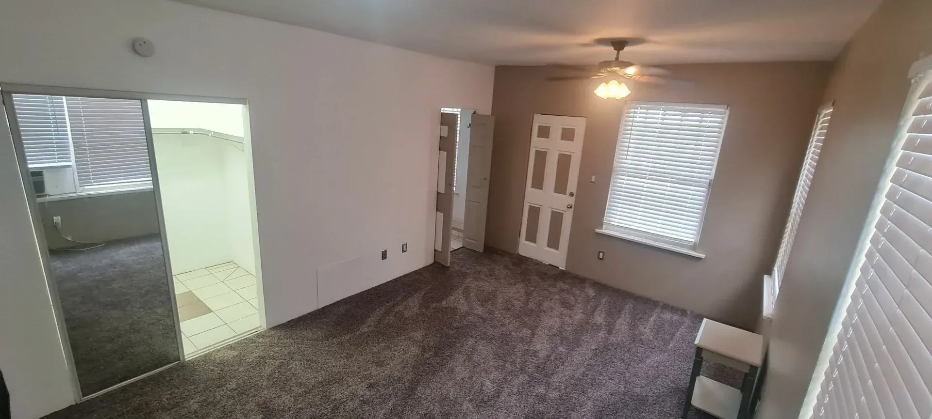 A living room with a ceiling fan and a carpeted floor.