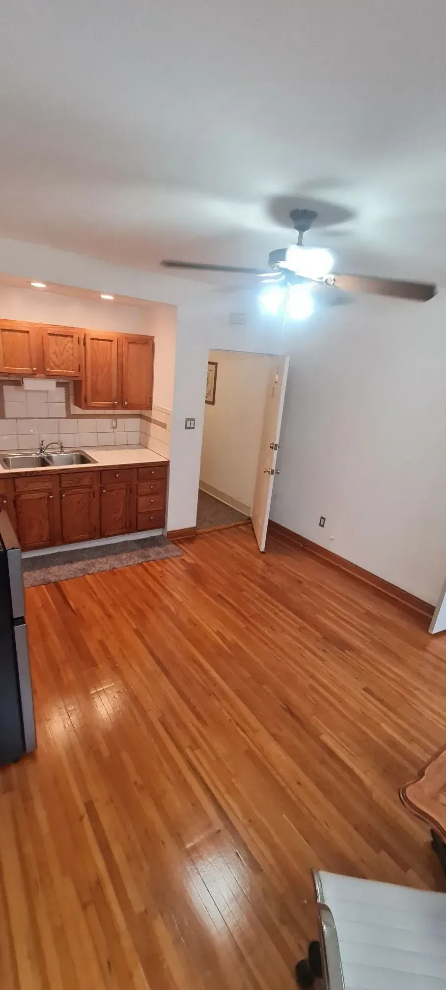 A living room with hardwood floors and a ceiling fan.