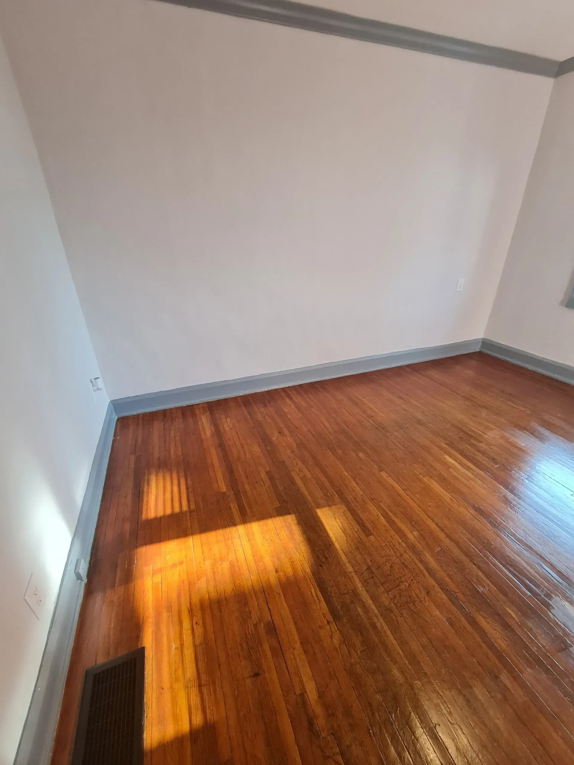 An empty room with hardwood floors and white walls.